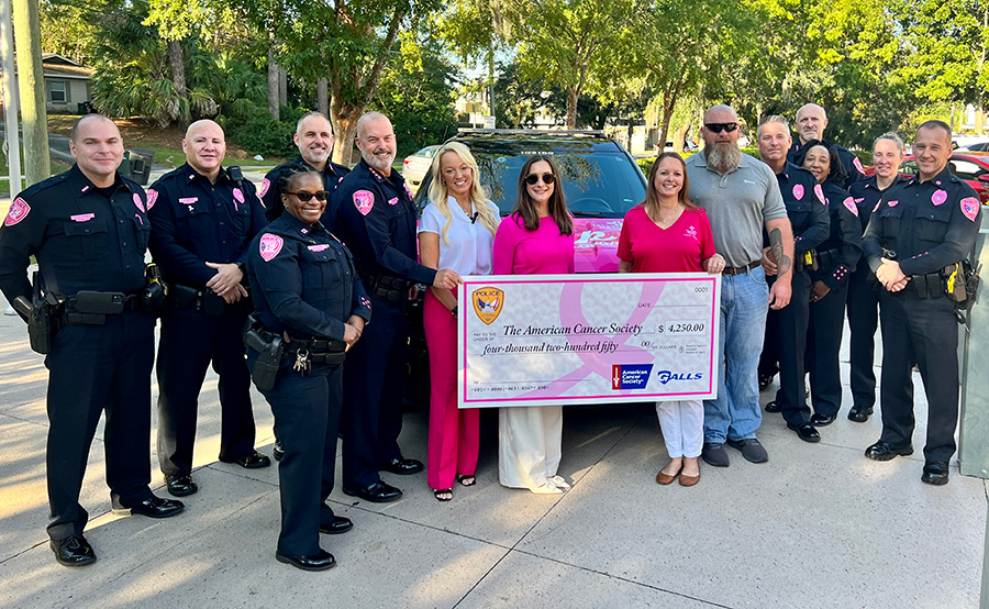 Officer in pink badges giving away a large check