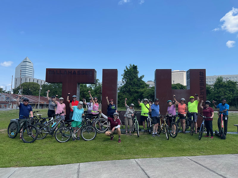 A group of bikers in front of the TLH art monument near Cascades Park.